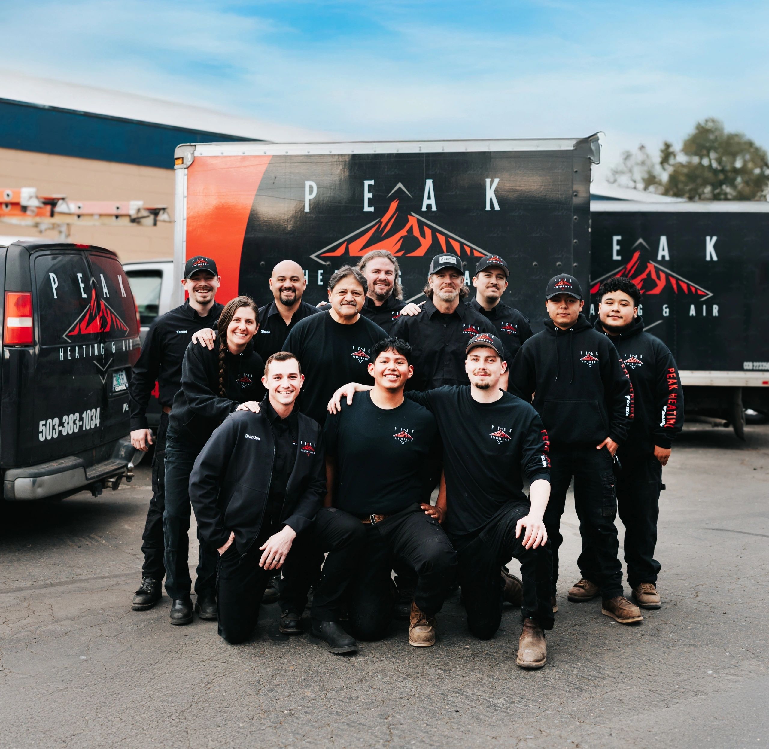 Peak Heating & Air team standing by company vehicles